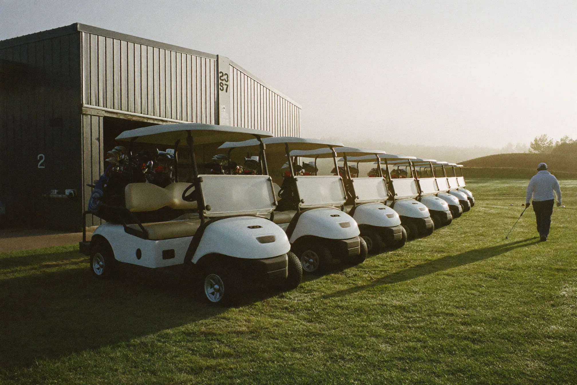 A row of golf carts charging outside the cart barn at dawn